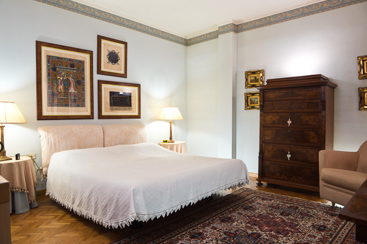 # Ulisse Albiati fotografo architettura interni: fotografia immobiliare camera da letto matrimoniale. Stile sobrio ed elegante, con autentico parquet in legno disposto a spina di pesce, tappeto persiano e papiri egiziani. Zona Prato, Toscana.