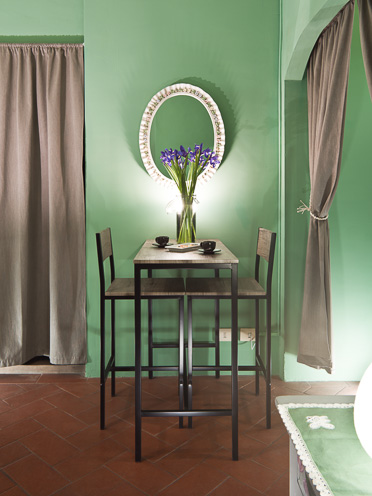 # Ulisse Albiati fotografo architettura interni: fotografia sala da pranzo minimale di un bed and breakfast. Pareti in colore verde. B&B, monolocale, ambiente unico e aperto in zona via delle Caldaie, nei pressi di piazza Santo Spirito a Firenze, Toscana.