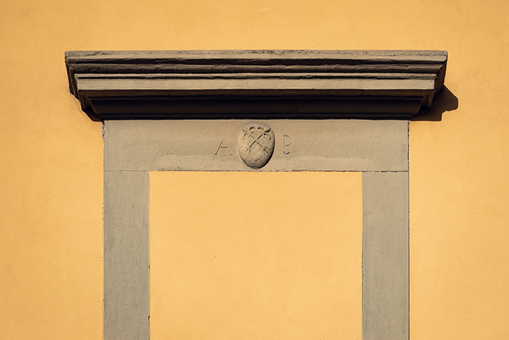 # Ulisse Albiati fotografo architettura esterni: fotografia immobiliare, dettaglio cornice in pietra serena di porta tamponata su facciata di edificio nell'antico e originario nucleo abitativo di Peretola. Firenze, Toscana.